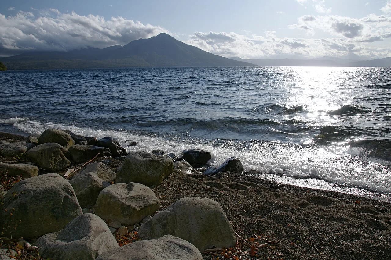 Mount Fuppushi across Lake Shikotsu, seen from its rocky shore.